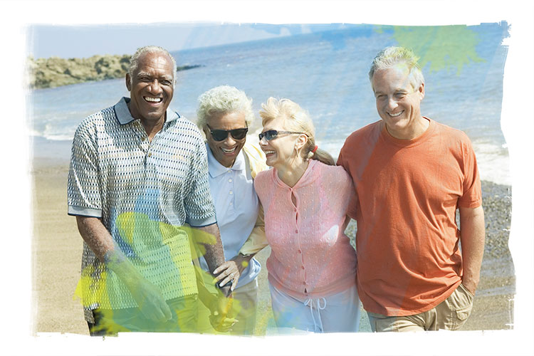 African American and caucasian mature couples walking on beach, laughing