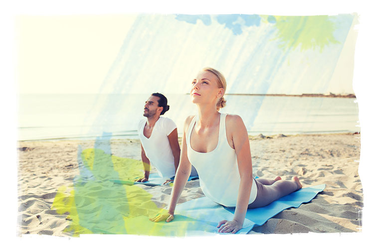 man and woman in upward dog position on beach