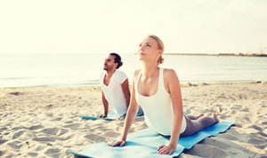 couple doing yoga on beach