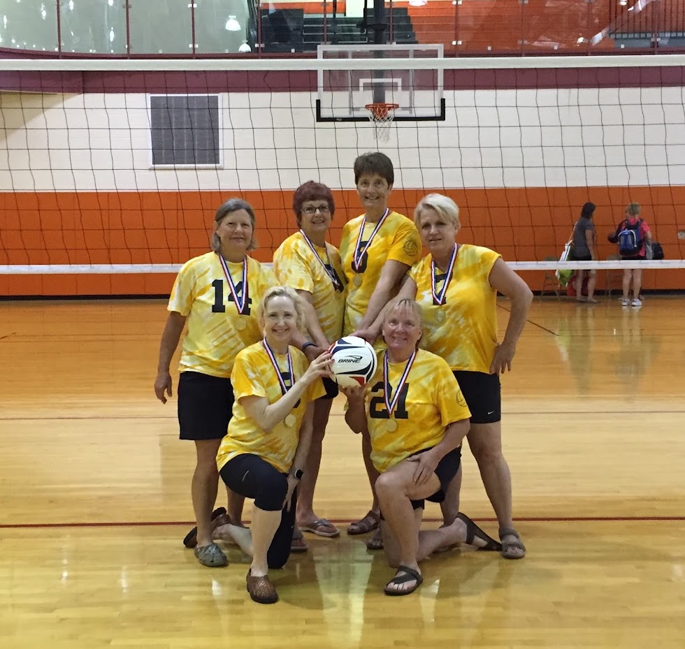 Senior athlete Nancy Brown posing with her women's volleyball teammates and their medals.