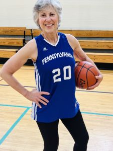 Paula Franetti, a woman standing on a basketball court holding a ball and smiling