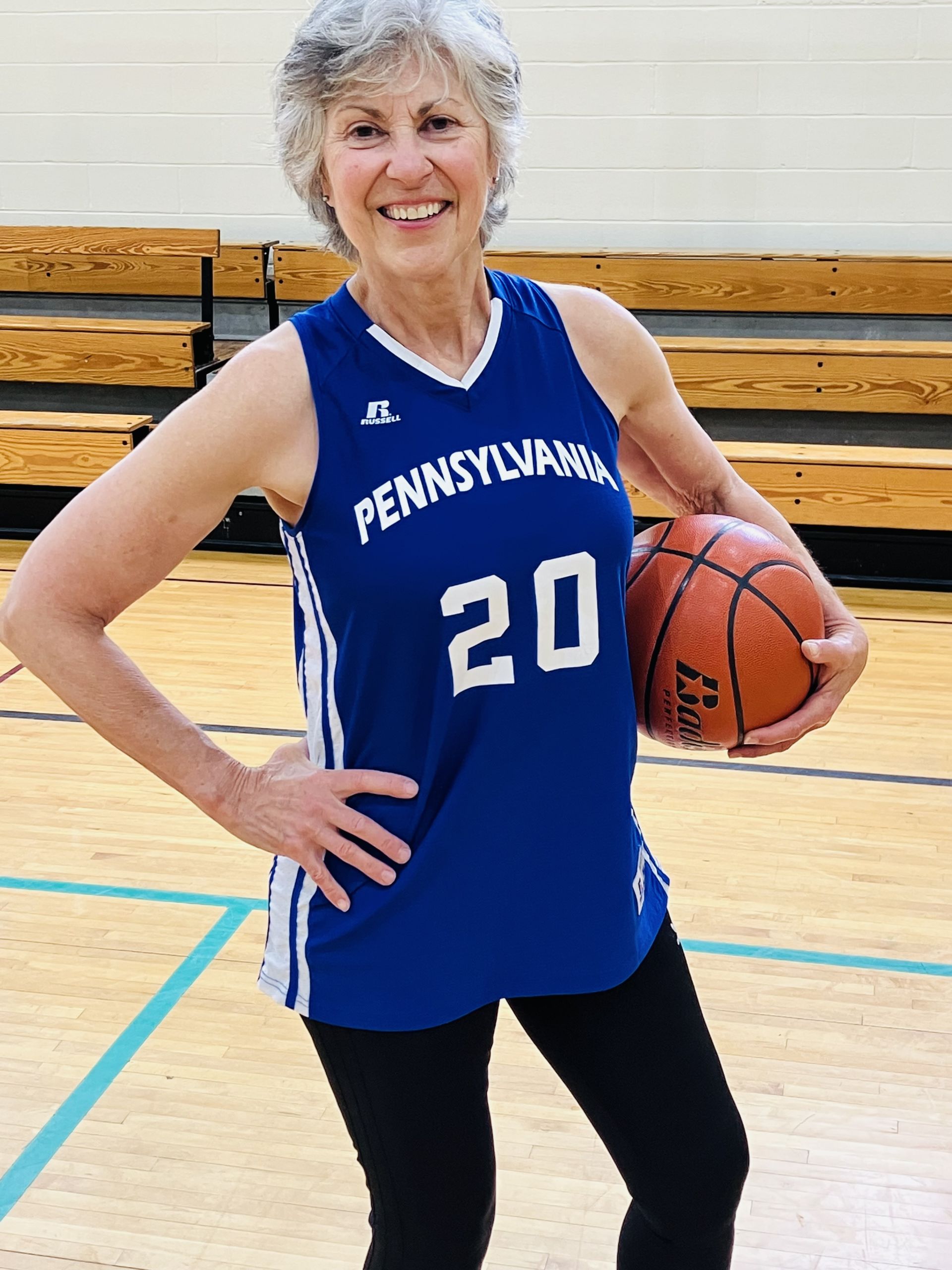 Paula Franetti, a woman standing on a basketball court holding a ball and smiling